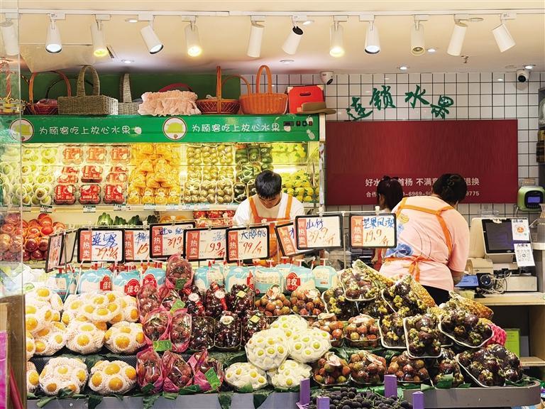 社区精品水果店内,店员正在操作台现切水果。