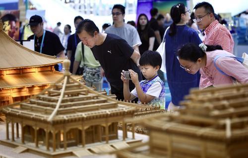 5月24日，深圳国际会展中心江西馆展区，一名小朋友拿着手机在“样式雷——北京中轴线”故宫三大殿建筑结构模型前打卡拍照。