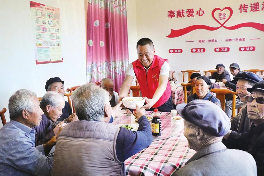 张家湾村党支部书记、村委会主任李小云正在爱心食堂为老人们送上热乎的饭菜