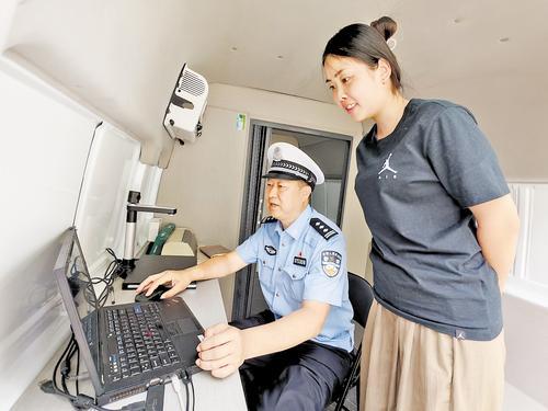 5月21日,在警邮联动便民服务车上,民警刘彦哲在审核驾驶证期满换证相关信息。 本报记者 刘 杰摄