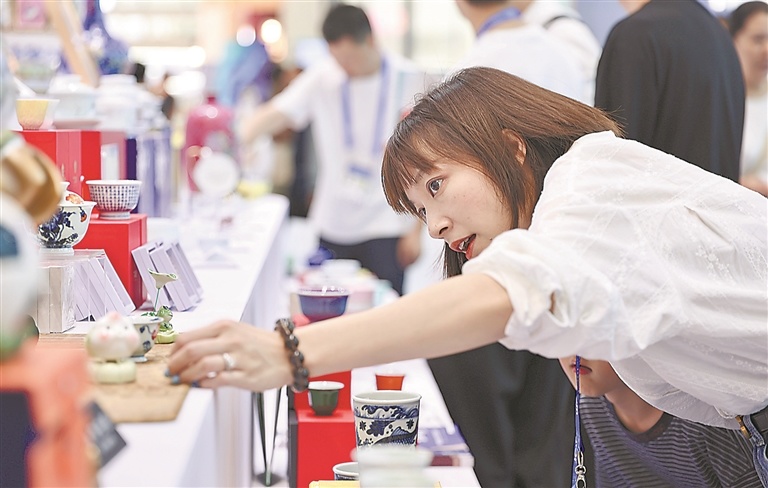 5月23日适逢周末,在深圳国际会展中心,第二十二届中国(深圳)国际文化产业博览交易会观者如潮。图为一名参观者在江西馆展区精心挑选瓷杯。江西日报全媒体记者 徐铮 摄
