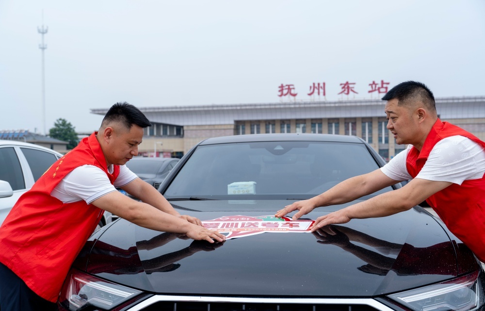 近日，在江西省抚州市东乡区站前广场，志愿者正在张贴“爱心送考”车贴。
