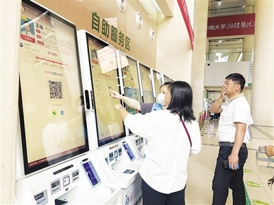 江西省人民医院红谷滩院区，市民在志愿者的引导下操作医保自助终端设备。