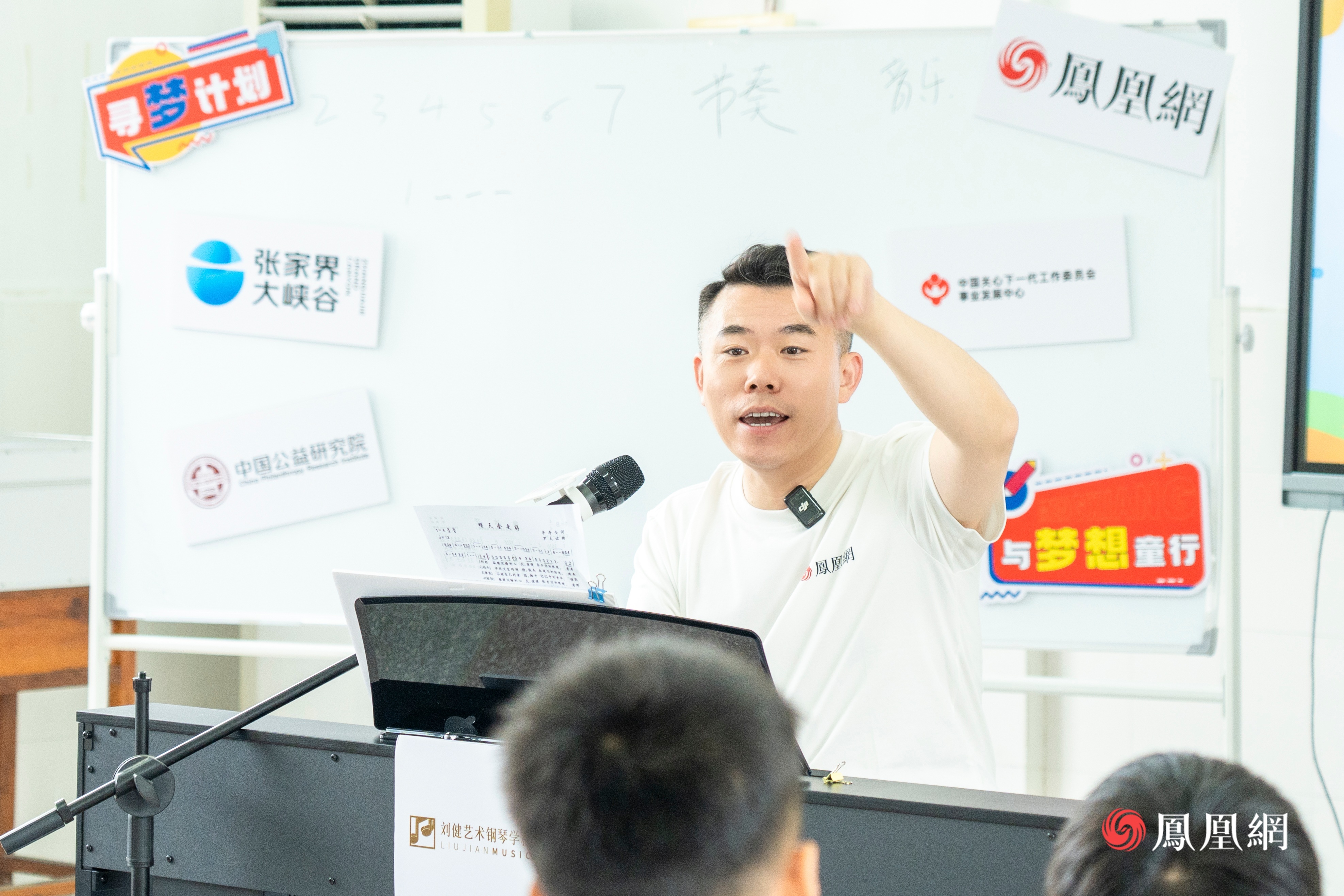 志愿者刘健为孩子们钢琴伴奏教学合唱