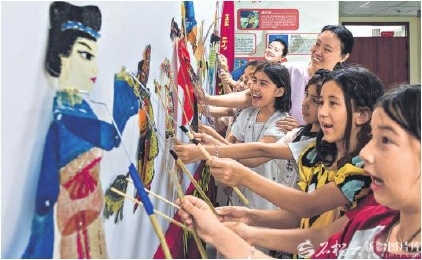 5月30日，乌鲁木齐市天山区胜利路街道羊毛湖社区开展“非遗迎六一 皮影伴童趣”活动，吸引了不少小朋友参加。图为小朋友在体验皮影戏表演。孙振嵩摄