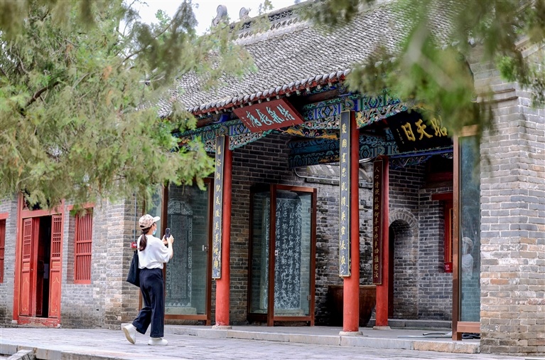 游人驻足岳忠武祠前，拍摄碑刻。