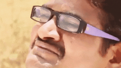 a man wearing glasses and a mustache is making a face .