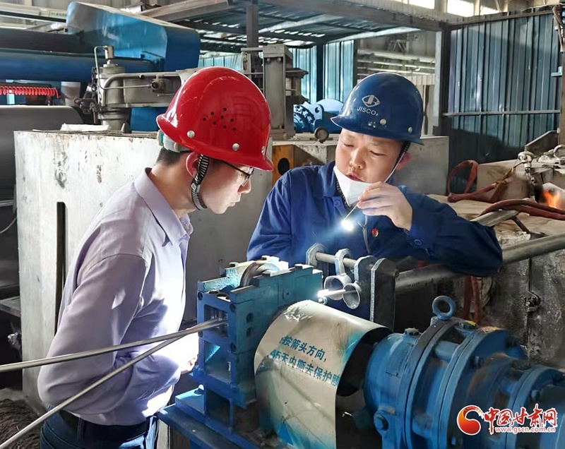 彭鹏（左一）在酒钢集团东兴铝业生产一线与工作人员交流技术问题