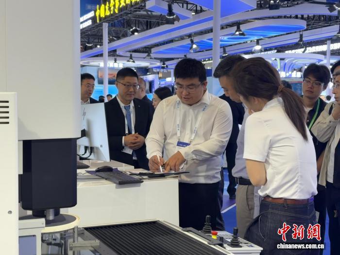 6月12日，吉林长春，卡尔蔡司展位工作人员与客户进行洽谈。　中新社记者 郭佳 摄