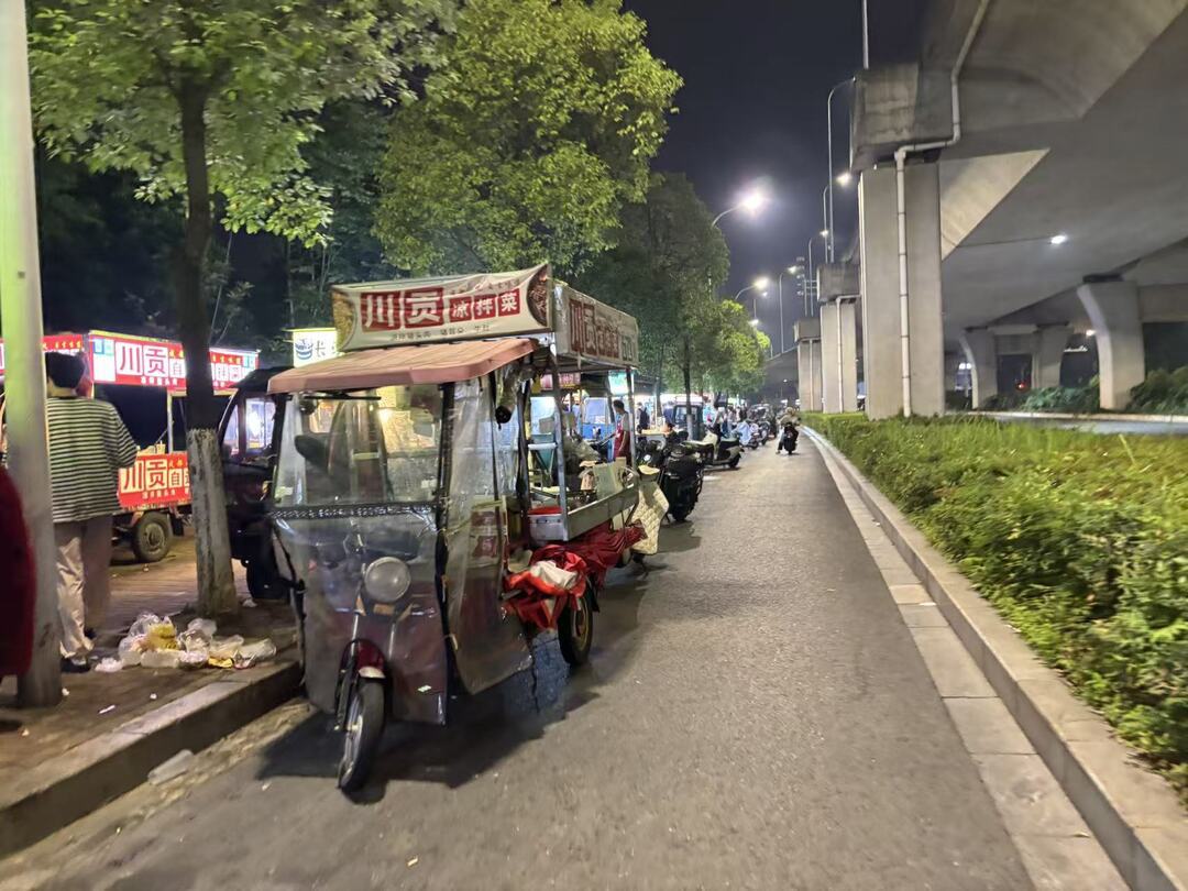 ▲有摊主将餐车摆在辅路上，地上散落垃圾