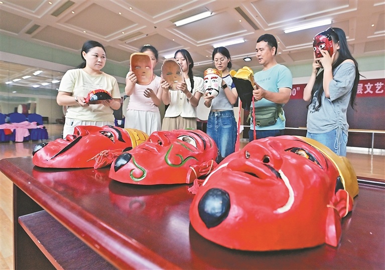 6月3日，德安潘公戏九江市非物质文化遗产代表性传承人桂海生（右二）在给学员介绍傩面具。