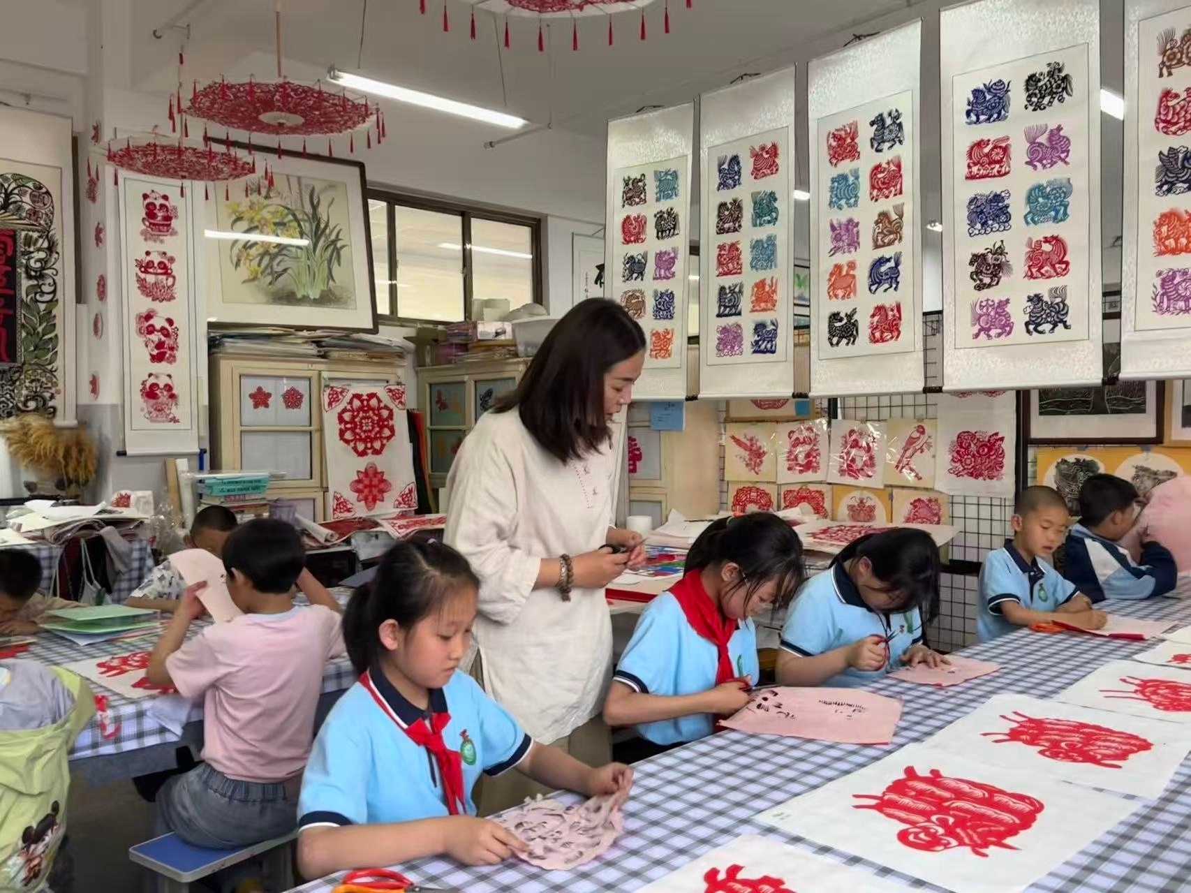 （图片为城南小学“宸雪剪纸工坊”美术教师周雪艳指导学生剪纸）