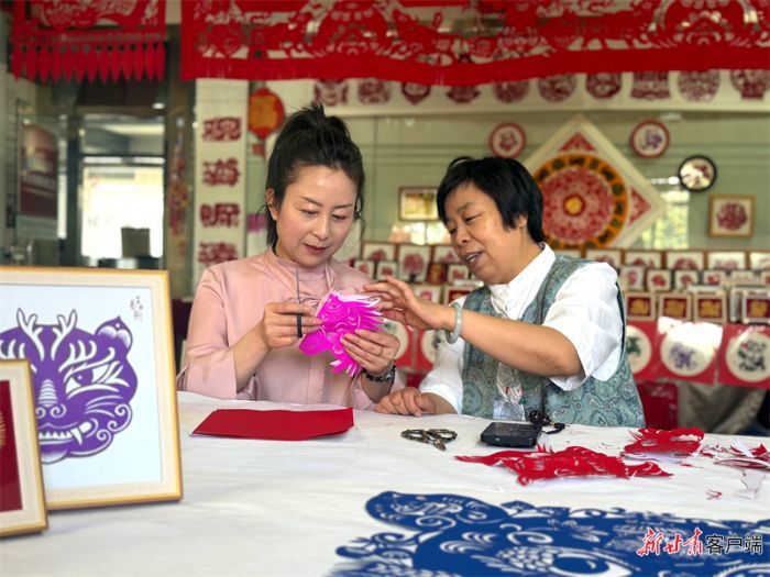马路（右）指导游客剪纸