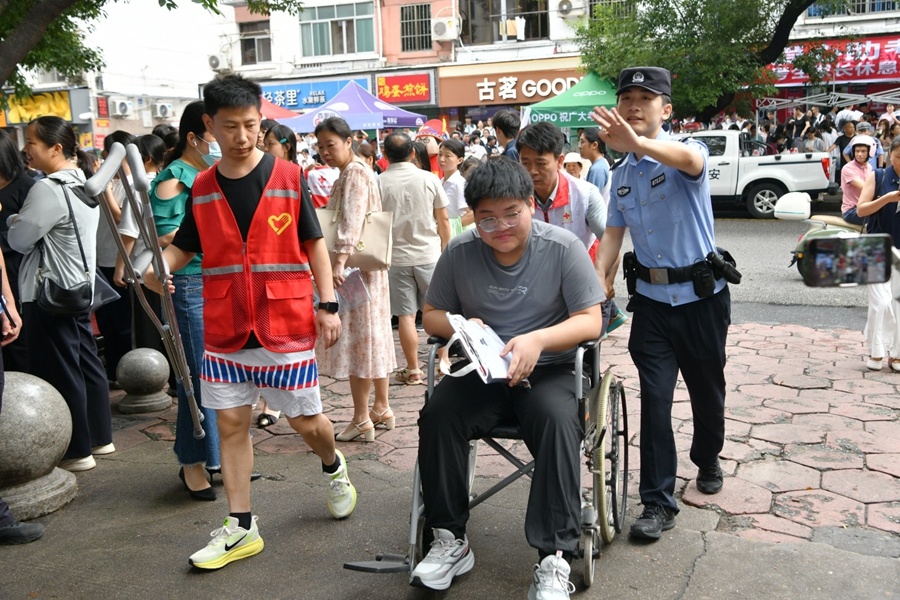 赣州一中考点,民警和志愿者护送受伤考生走进考场。