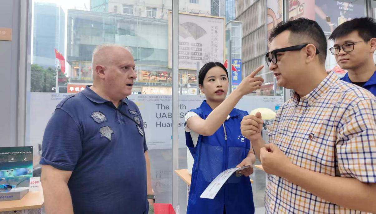 公务员服务队在华强北全球人工智能应用场景中心为外国游客作产品导购。