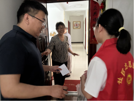 图:社区志愿者正在入户为居民送粽子。尹默/摄