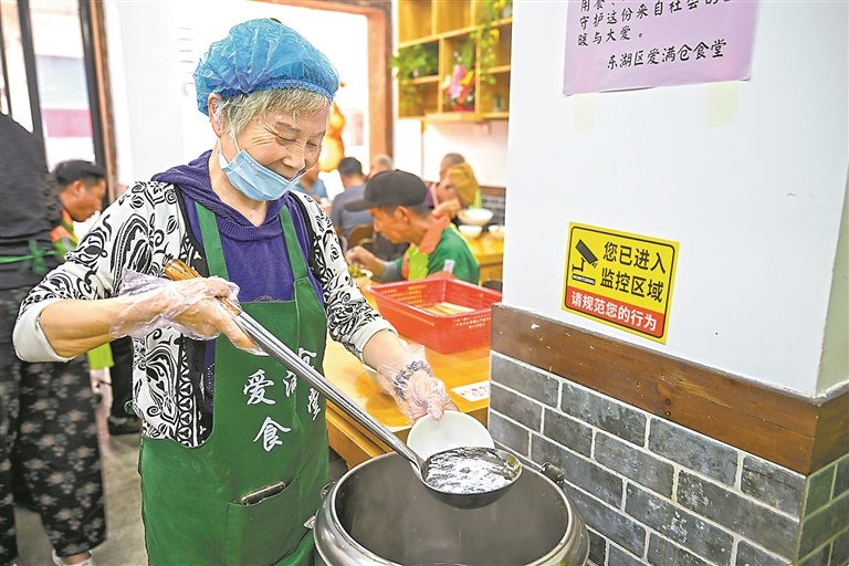 志愿者为腿脚不便的老人盛汤。