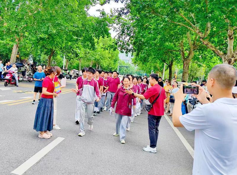 在西安高新第三中学考点外，来自西安市高新第一学校的送考老师们为考生鼓劲加油，家长用手机记录下这一幕。（首席记者 程静 通讯员 王华清摄）
