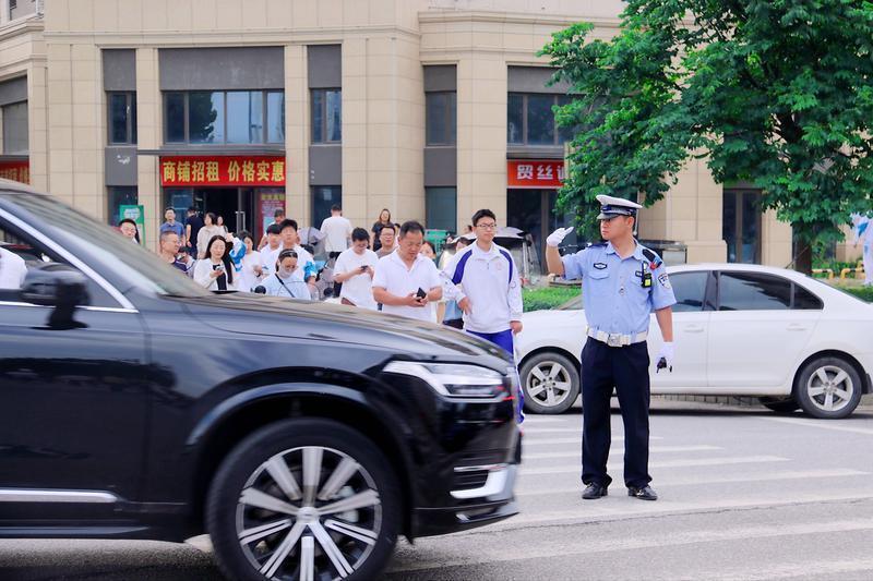 在西安市高新第一学校考点，考生有序走进考点，交警在外围疏导交通。