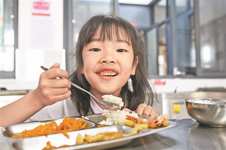 吃着可口的午饭，孩子脸上洋溢着幸福的笑容。