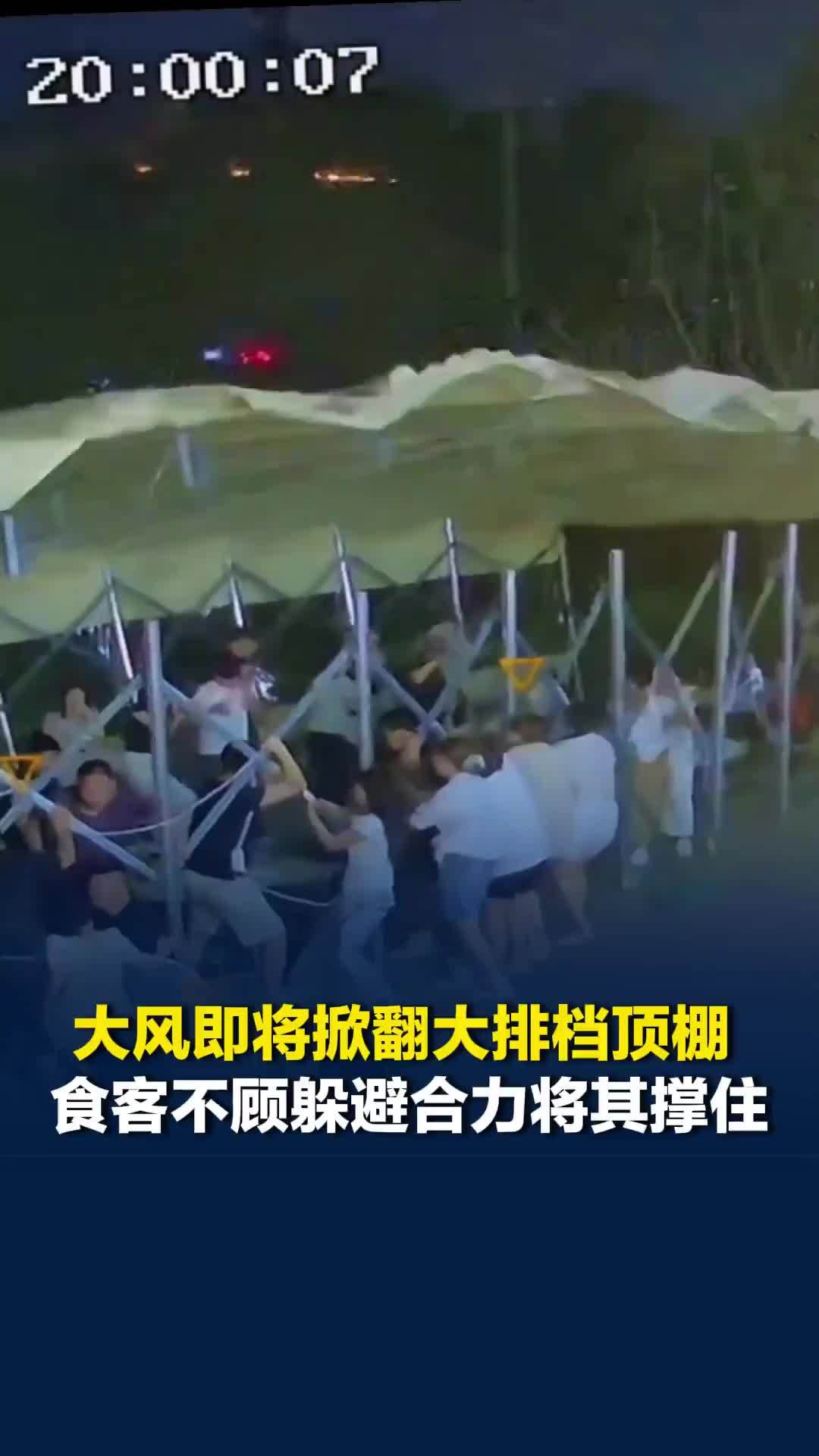 大风即将掀翻大排档顶棚，数十名食客不顾躲避合力将其撑住，老板当场宣布全场免单