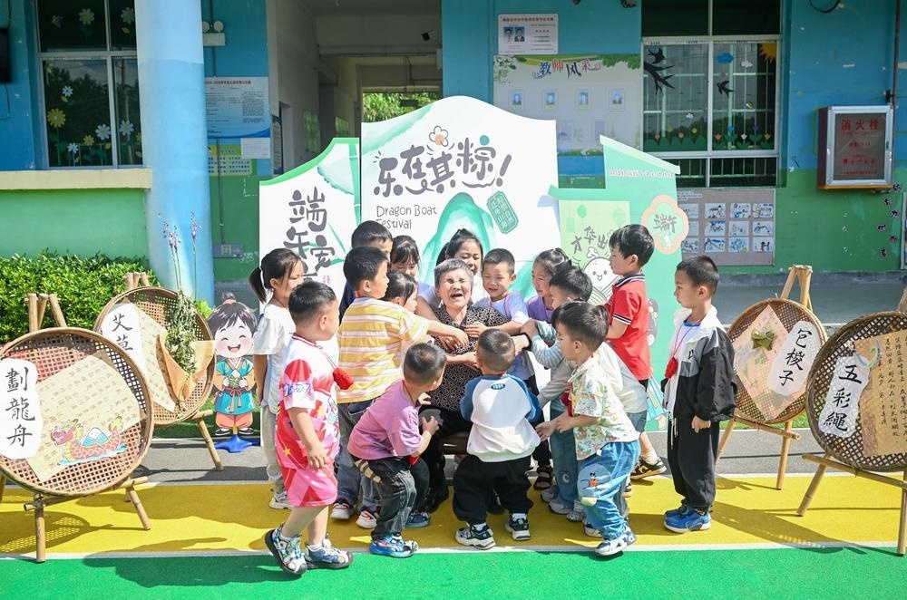 刘孝英老人给铜鼓县高桥乡中心幼儿园的孩子们讲童谣故事，孩子们拥抱感谢。