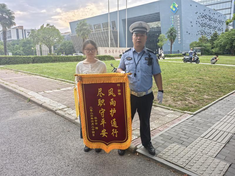 图说：护学岗民警郭伟（右）接收群众送来的锦旗。