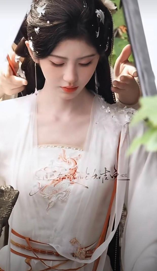 搜狐娱乐讯 近日，一组鞠婧祎新剧外景路透曝光，她身穿素白古风长裙搭配精致羽毛发饰，飘逸古装造型清灵脱俗，温柔婉约仙气十足。