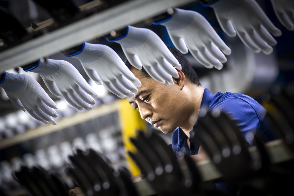 工人在星宇安防科技集团生产流水线上整理浸胶手套。新华社发