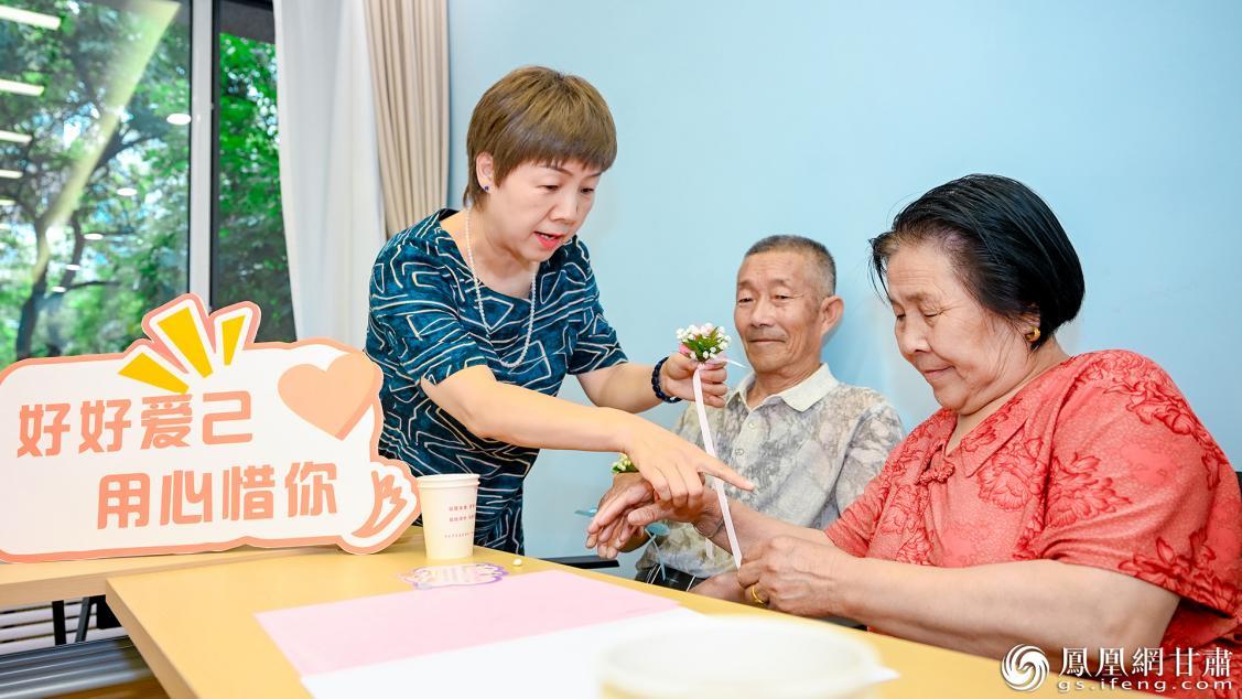 甘肃省妇联工作人员(左)帮助长者夫妻佩戴爱的花环