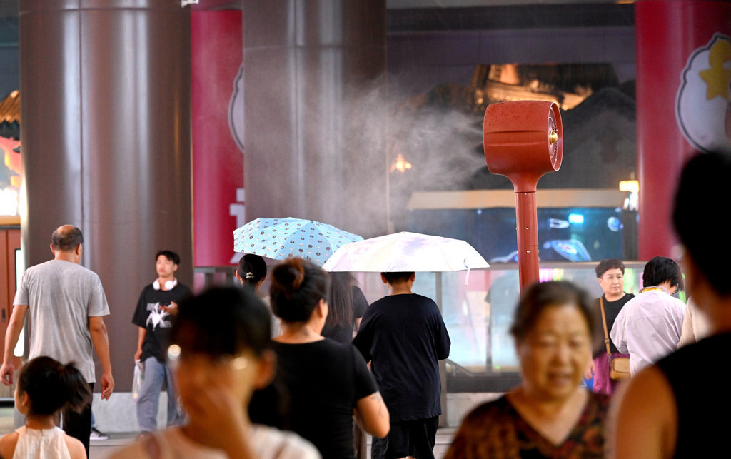 7月21日，在邯郸市邯郸道历史文化街区，游客从雾森风扇旁经过。