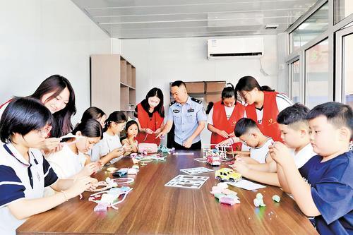 7月17日下午，唐山市路南区天地福农水果批发市场警务小屋内，民警张彩杰和志愿者们指导小朋友们做手工。本报记者 靳庆军摄