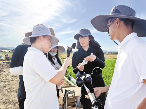6月22日,河北鹿泉现代节水农业科技小院试验田,河北省科技创新服务中心副研究员蔡东玉(左前)正和学生们安装气象站。本报记者 白 云摄