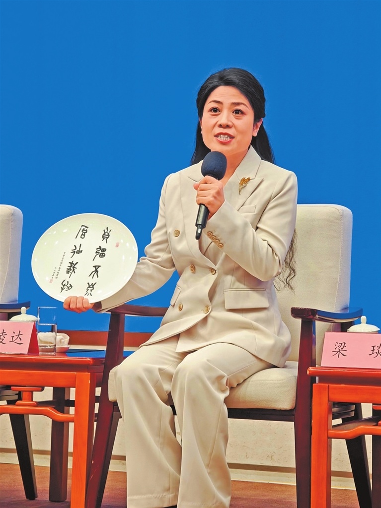 在见面会现场,梁琰向中外记者展示听障学生的甲骨文刻瓷作品。记者 程帅星 摄