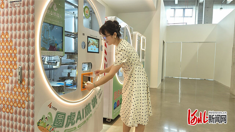 7月19日,在大虎智源(香河)科技有限公司展厅,客商在拿取AI煎饼机器人制作好的煎饼。河北日报记者 刘 英摄