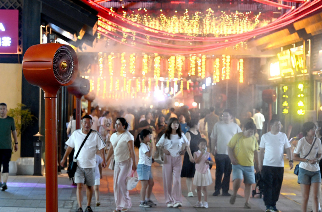 7月21日，在邯郸市邯郸道历史文化街区，游客从雾森风扇旁经过。