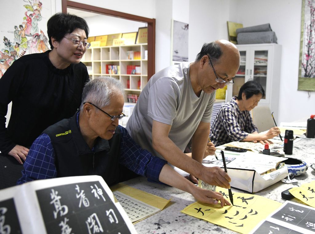 滨河社区老年志愿者(右二)给其他老人指导书法技巧。(孟瑶 摄)