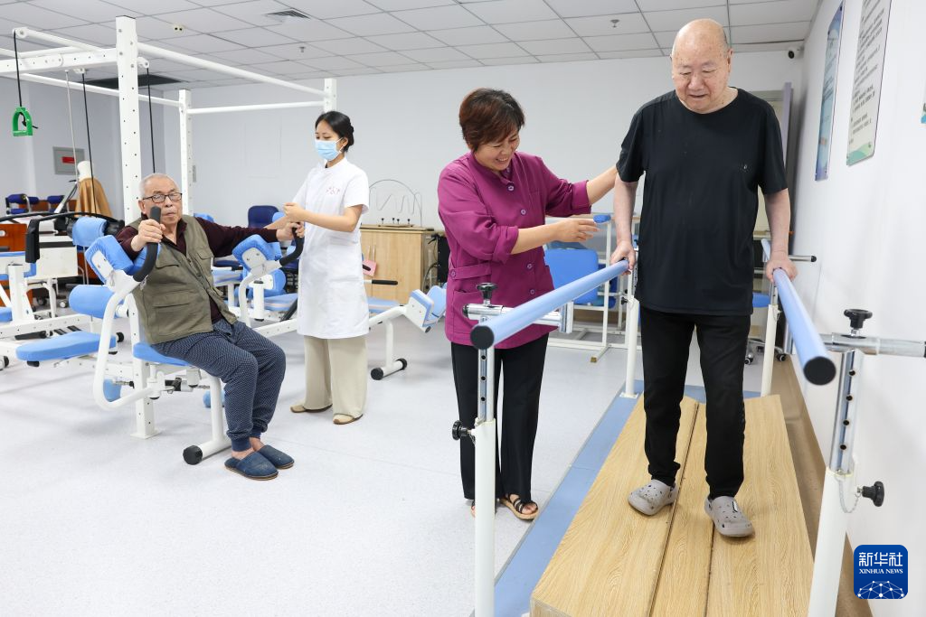 7月23日,在河北省石家庄市元氏县福缘养老院,工作人员帮助老人进行肢体运动康复训练。
