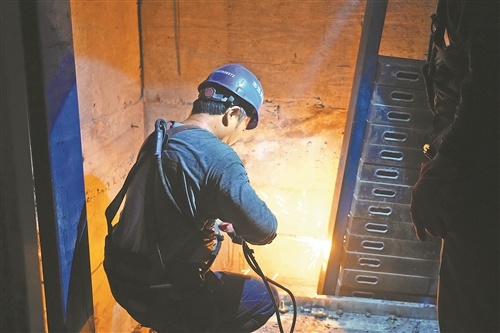 工人正在电梯井内进行旧电梯拆除工作。本报全媒体记者 蔡颖辉摄