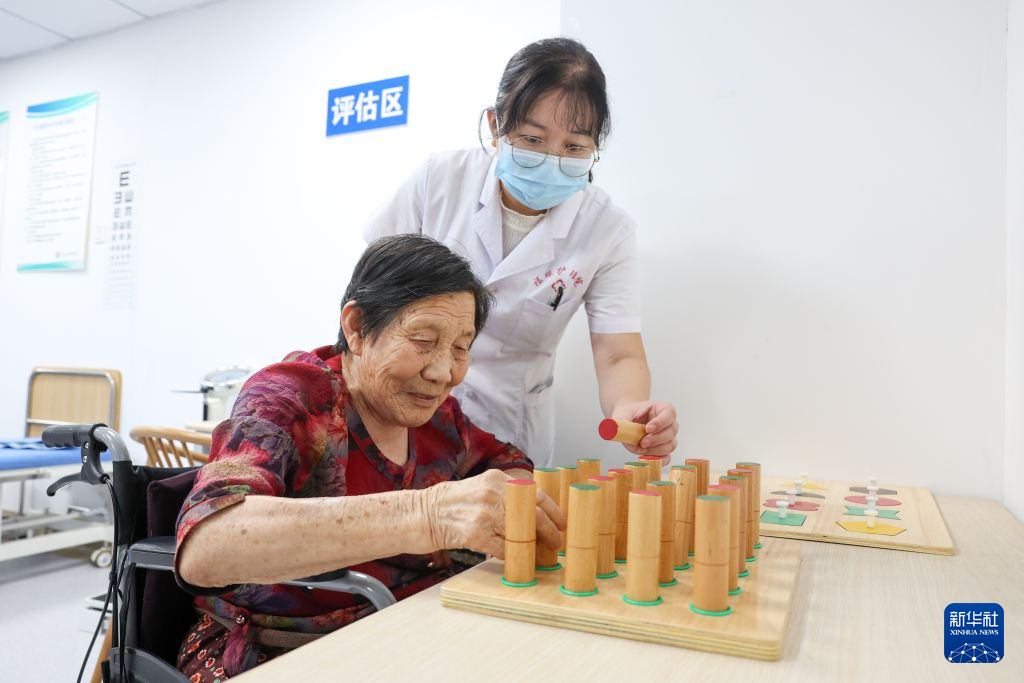 7月23日,在河北省石家庄市元氏县福缘养老院,工作人员帮助老人进行手部功能训练。