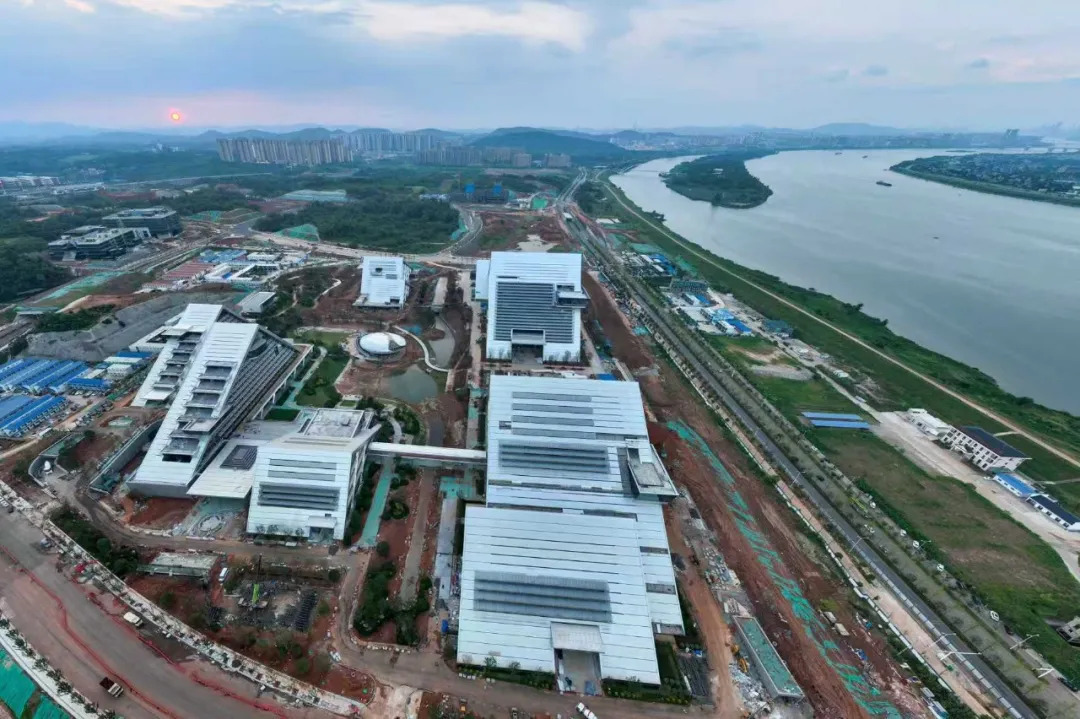 (湘江科学城建设现场一片繁忙,银白色几何造型建筑群沿湘江铺展。目前,项目主体已初具规模,周边道路、绿化及配套工程同步推进。江毅 摄)
