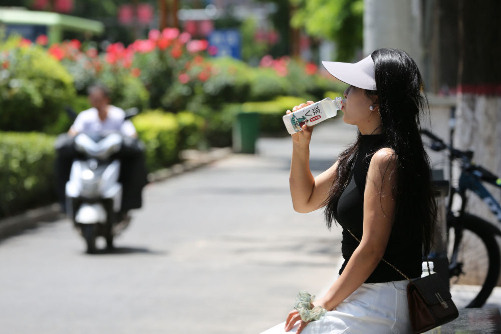 7月28日,在甘肃省天水市武山县街头,一名女士喝浆水饮料解渴。新华社发(王克贤 摄)
