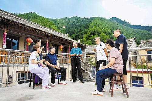 7月29日,孙振泽(左四)在自家民宿向游客介绍骆驼湾村的变化。本报记者 张 昊摄