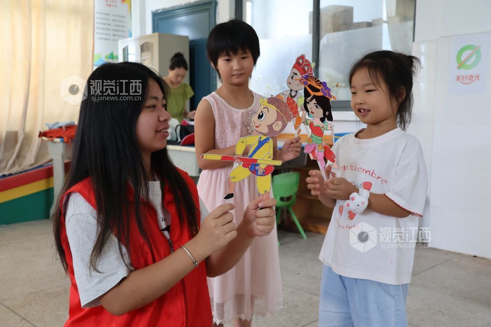 2026年7月28日,在江西省吉安市吉州区兴桥镇兴桥中心小学童心港湾,志愿者正在陪伴孩子们出演皮影小戏。