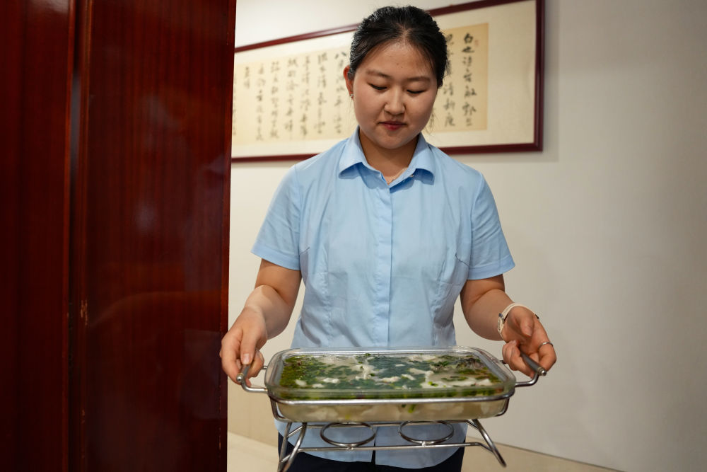 7月24日,在甘肃省白银市会宁县一家宾馆,服务员为顾客端上一份浆水鲈鱼。新华社记者 郎兵兵 摄