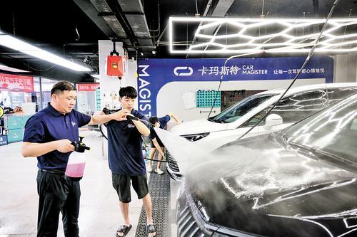7月20日，苏长奎（左）给员工讲解洗车技巧。本报记者 张 昊摄