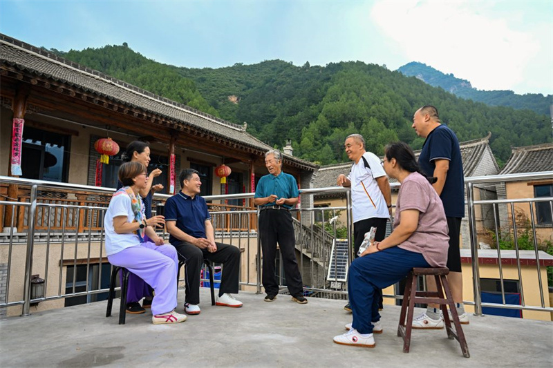 7月29日，村民孙振泽（左四）在自家民宿向游客介绍骆驼湾村的变化。