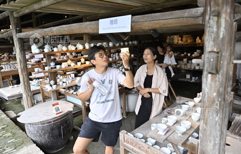 景德镇陶阳里历史文化街区内的徐家窑作坊群，手工艺人向游客讲解制瓷技艺。