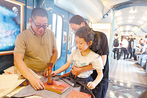试乘儿童旅客在“武夷山国家公园”主题观光列车上体验国家级非物质文化遗产“建本雕版印刷技艺”。