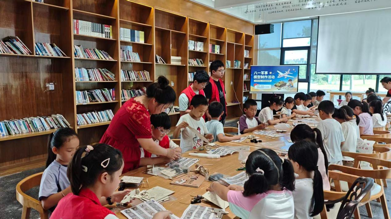 志愿者和家长正在指导孩子们拼装自己心仪的军事装备